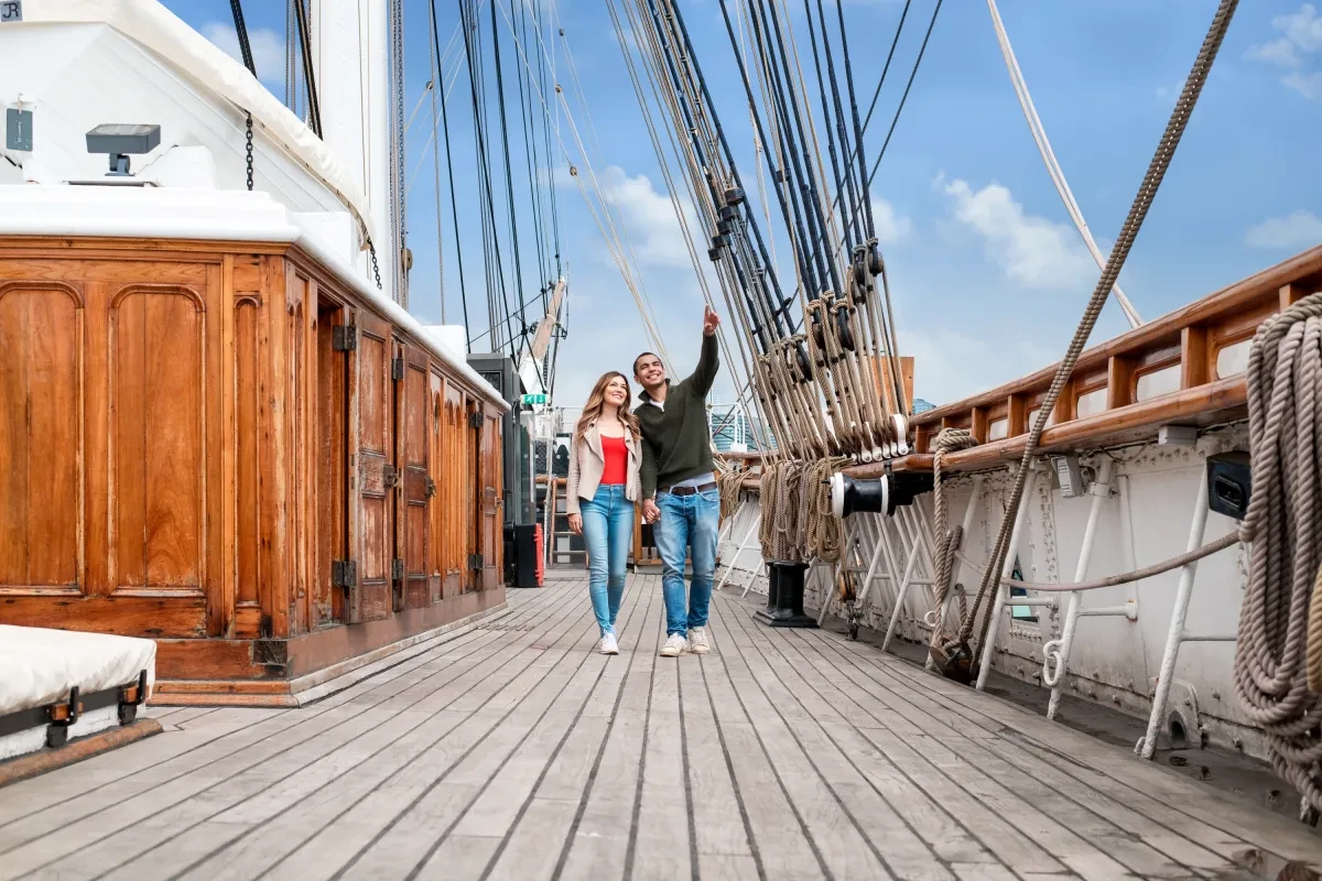 A man and a woman walk along the main deck during a visit to Cutty Sark