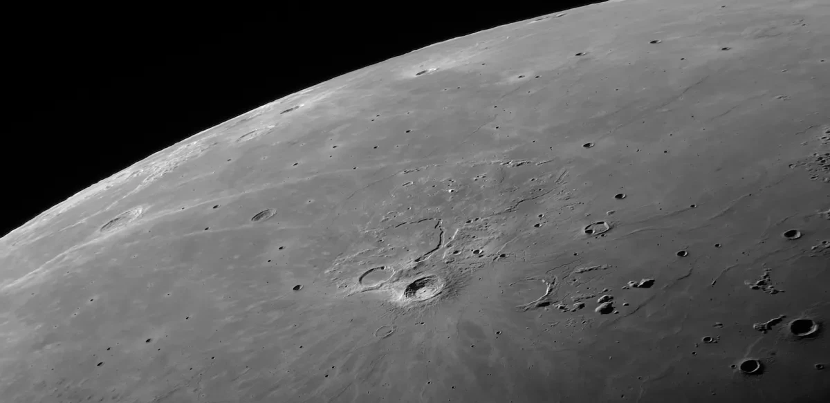 Photo zoomed into top left corner of Moon, with surface rendered in excellent detail with a few craters and mountains visible