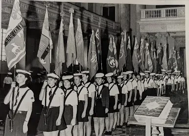 Photograph of a uniformed Sea Rangers procession with flags being carried in a hall.