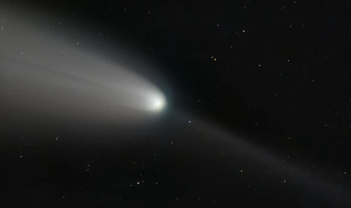 A white comet streaks across a dark sky