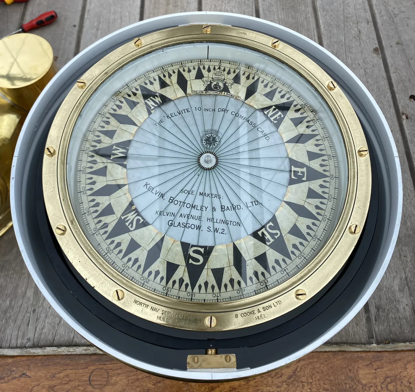A close up detail of a historic gold and black compass inside Cutty Sark's binnacle