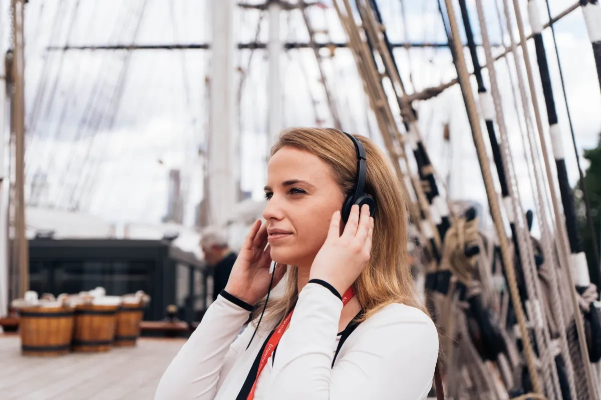A woman listens to a museum audio guide on board Cutty Sark. She is wearing headphones