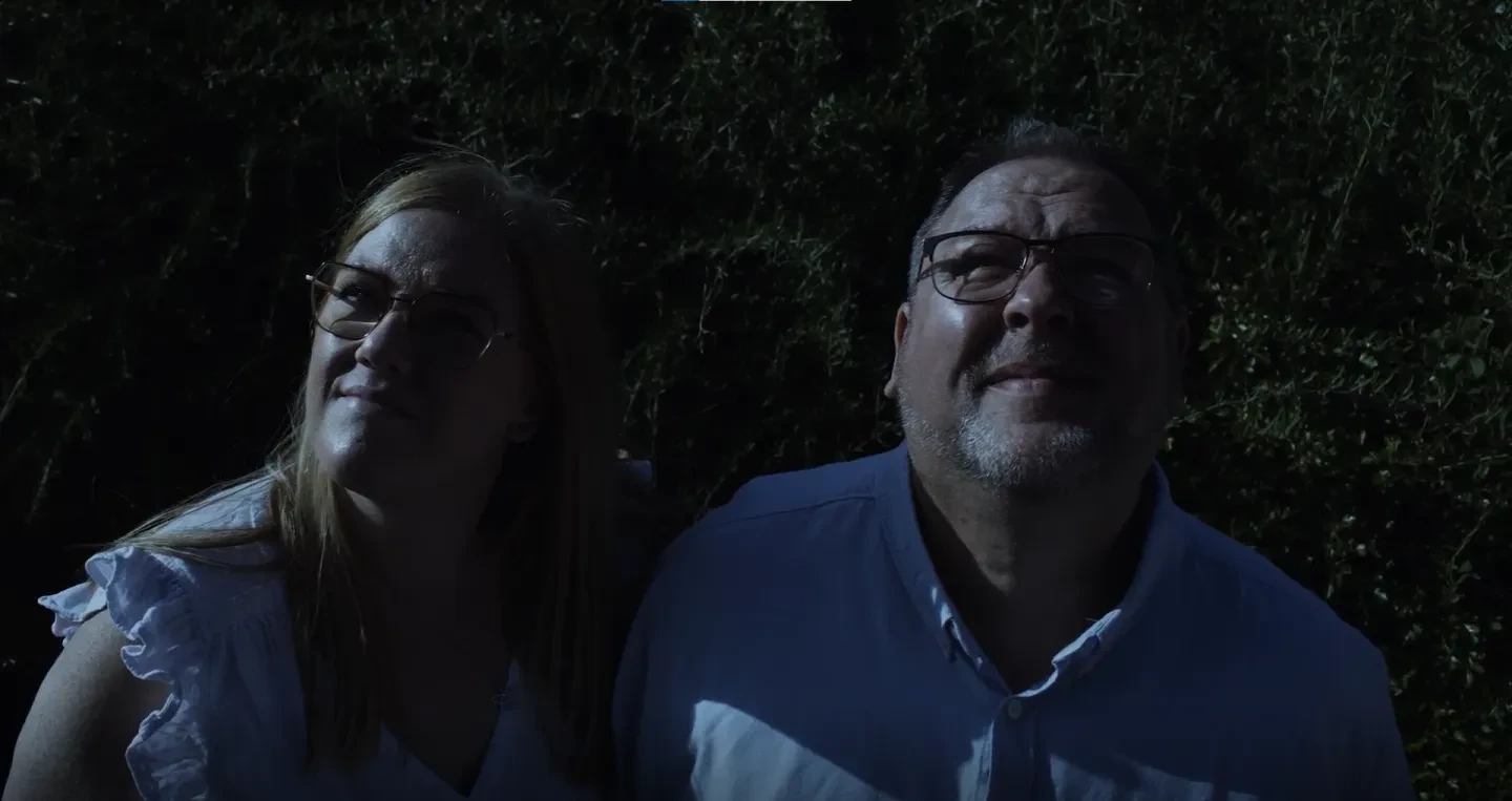 Darren and Claire Flinders in semi-darkness looking up at the sky and smiling