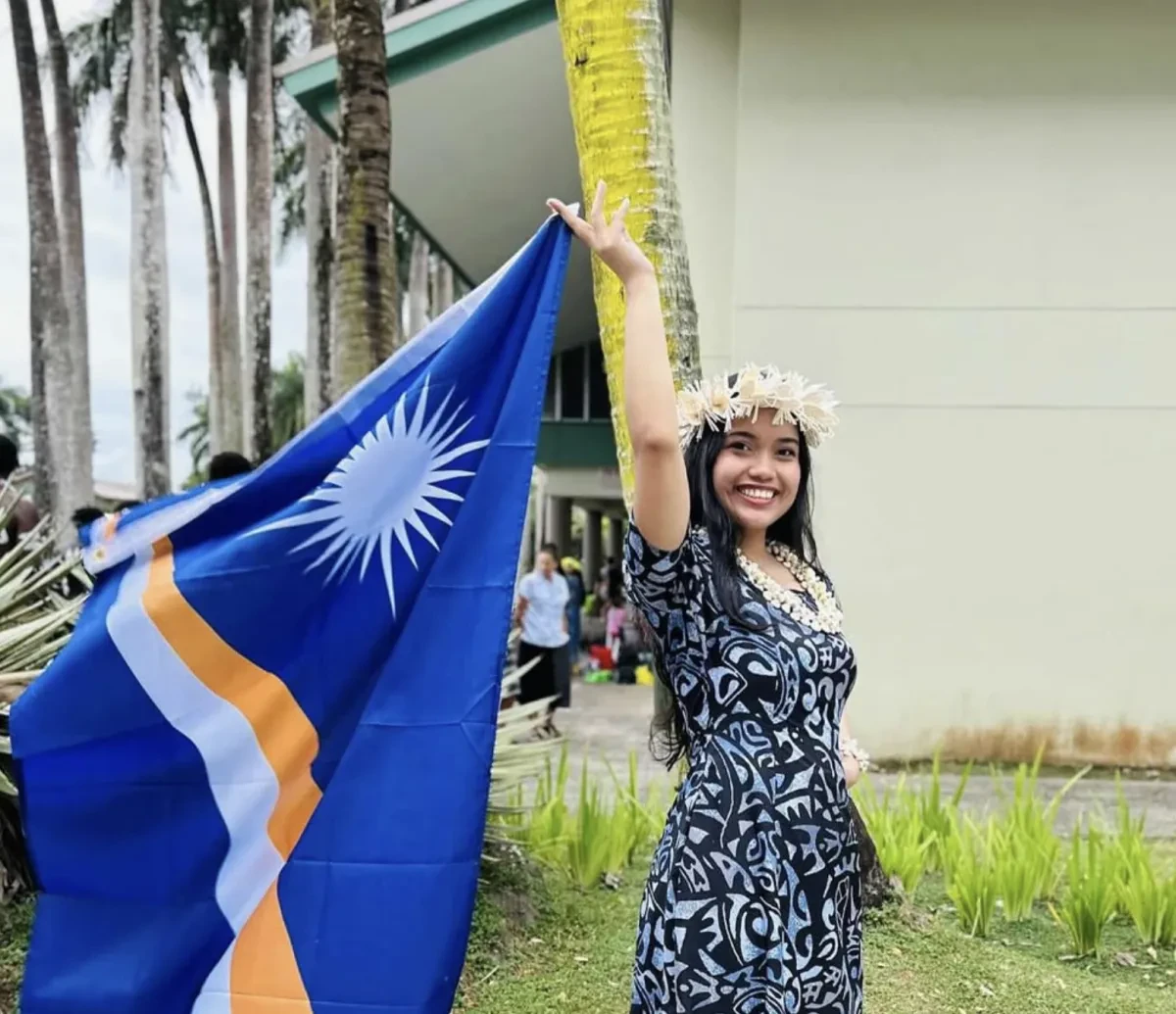 A photograph of Debby Schutz holding the flag of the Marshall Islands