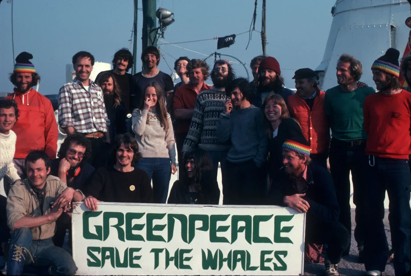 The crew of Rainbow Warrior holding a banner saying 'Greenpeace: Save the Whales' in 1978