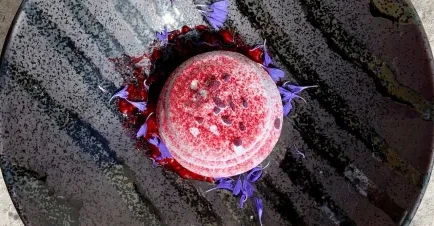 A bright dessert served on a dark grey plate