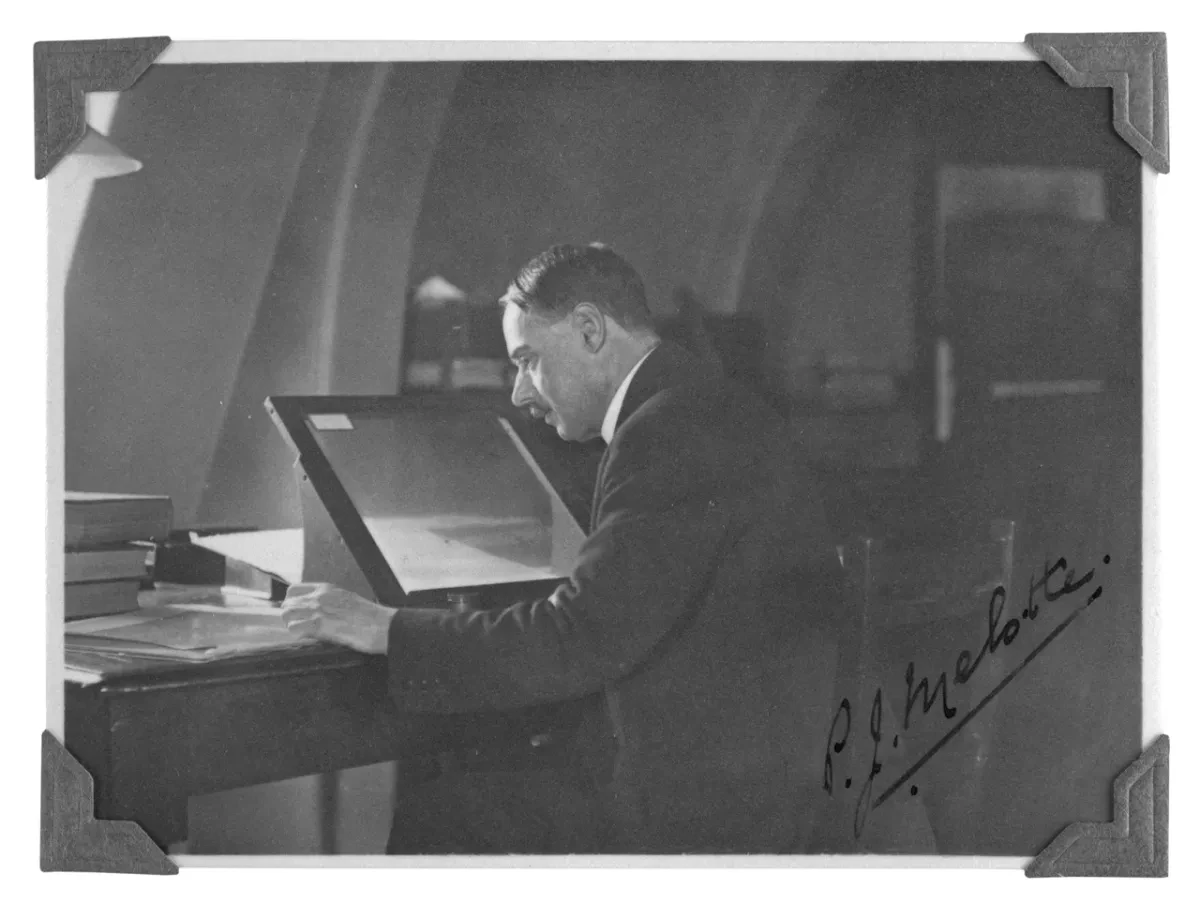 Old black and white photo of P.J Melotte sitting and looking at photographic plate