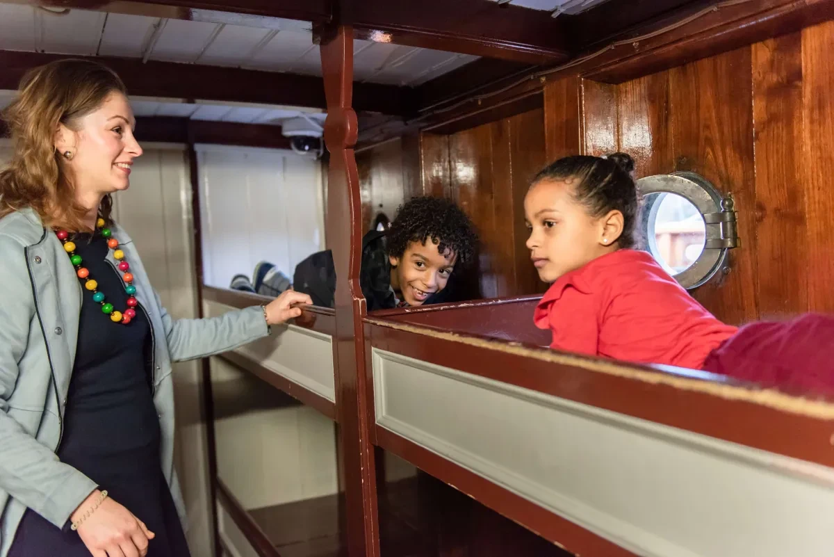 A woman and kids explore the Cutty Sark's bunk beds.