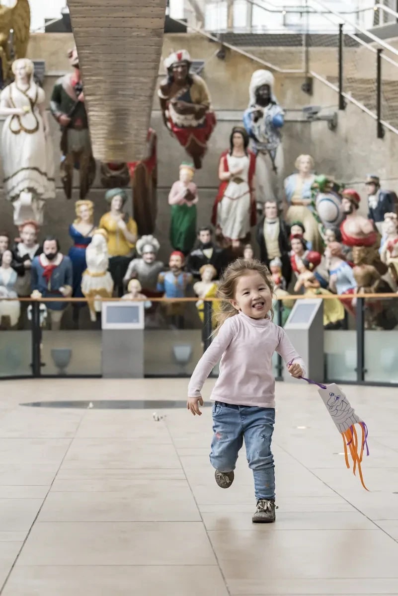 Toddler running in front of the figureheads 