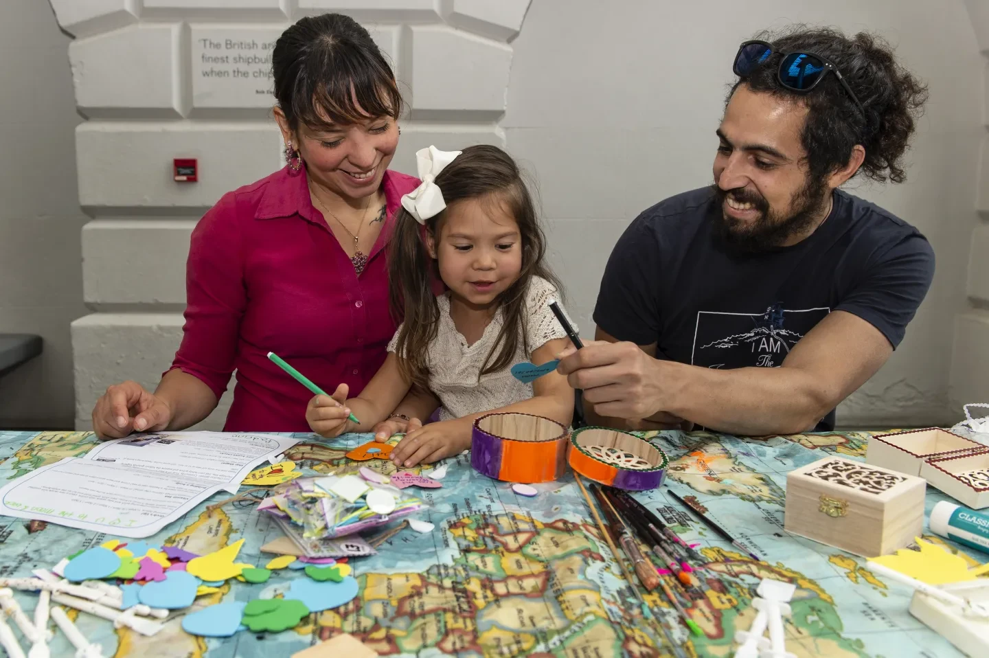 Two parents and a child play with craft materials.