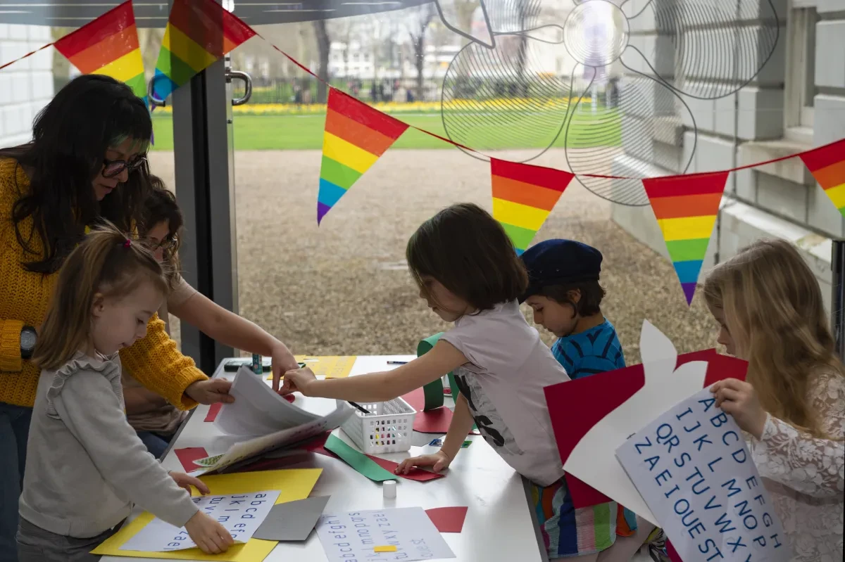 A group of children take part in a craft activity, with Pride flag bunting on display.