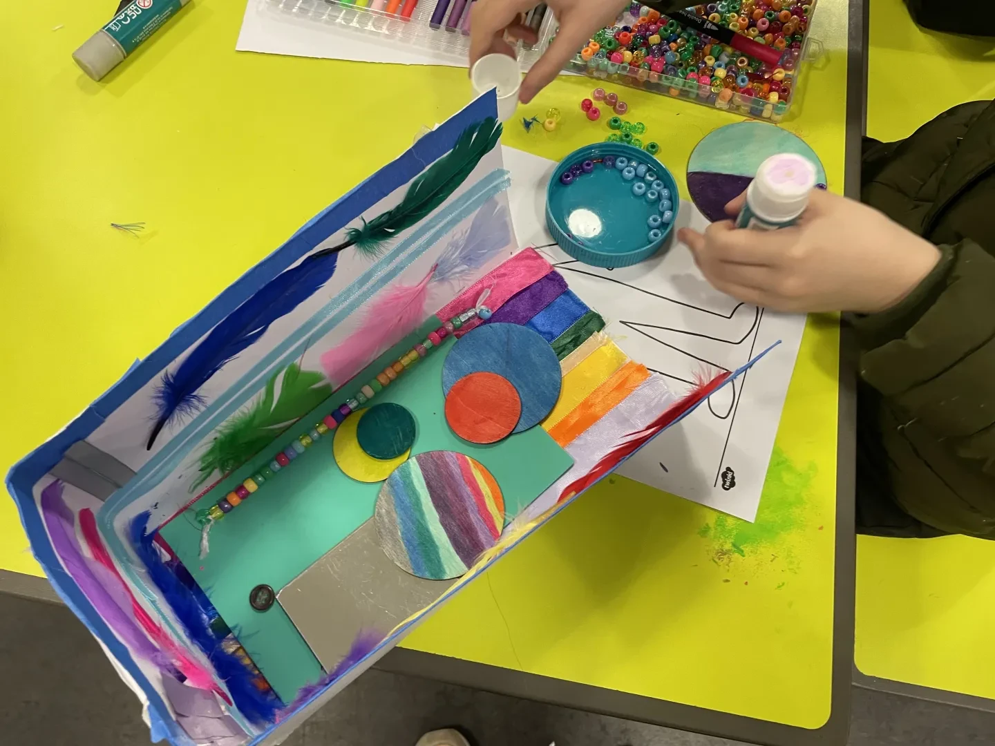 Saturday Art Club member uses glue and sequins to make an artwork