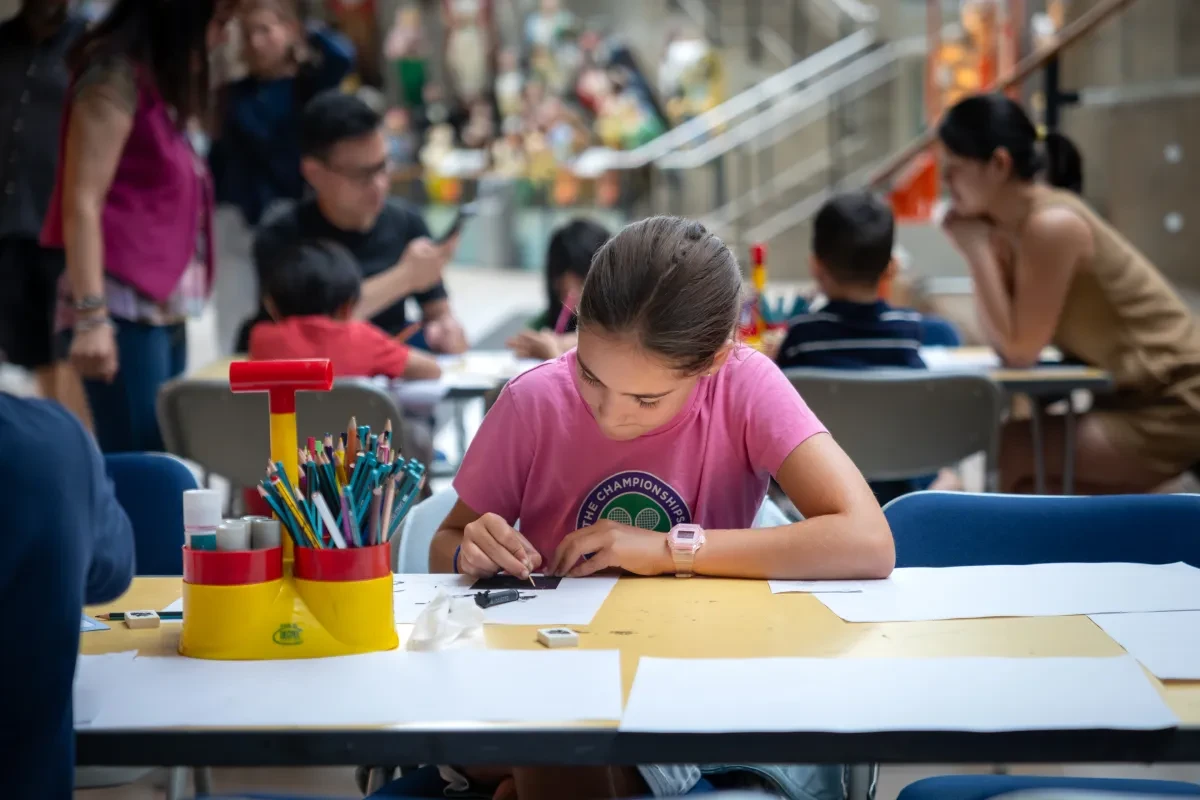 Child using pens on paper sitting at table at Cutty Sark