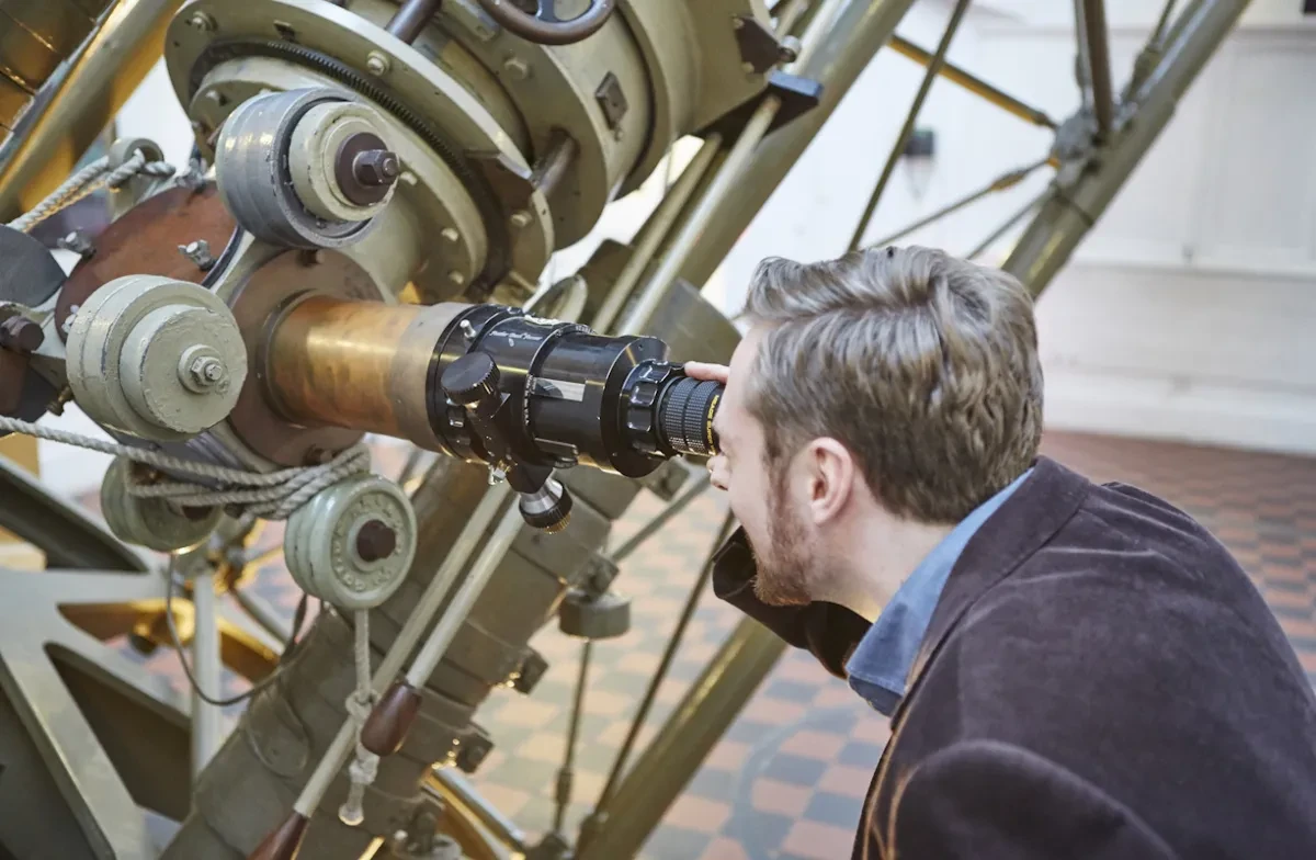 A man looking into a large telescope.