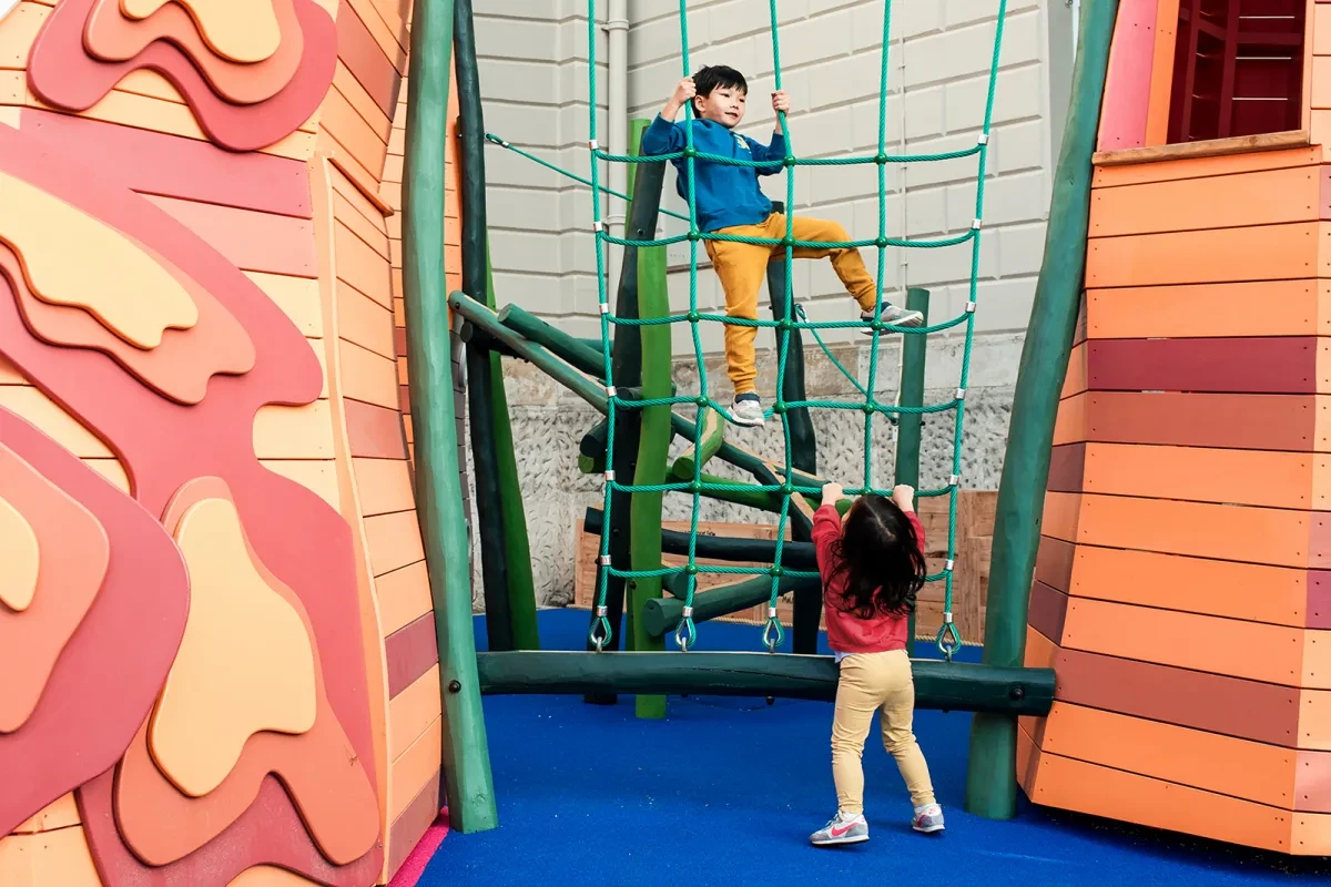 A boy climbs a cargo net in The Cove playground.