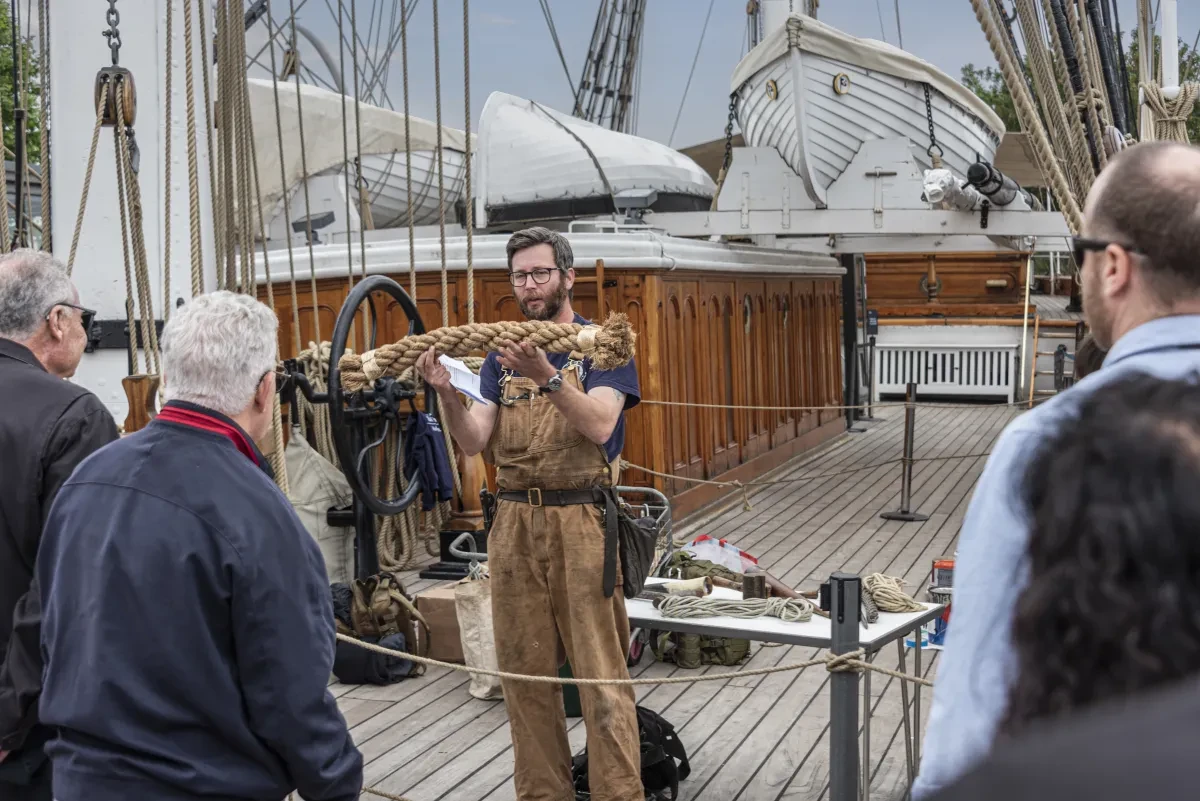 Person holding up a braided rope on the main deck of Cutty Sark