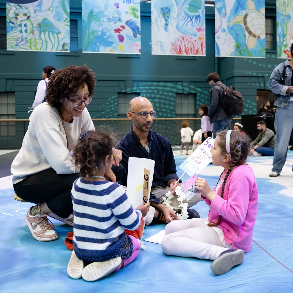 A family of four sitting together on a large floor map of the ocean at the National Maritime Museum